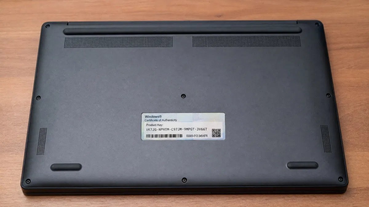 Laptop turned upside down on a desk showing a Windows certificate of authenticity sticker with a product key printed on it