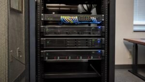 Server rack in a small office room with three rack-mounted servers and a network switch with status lights lit